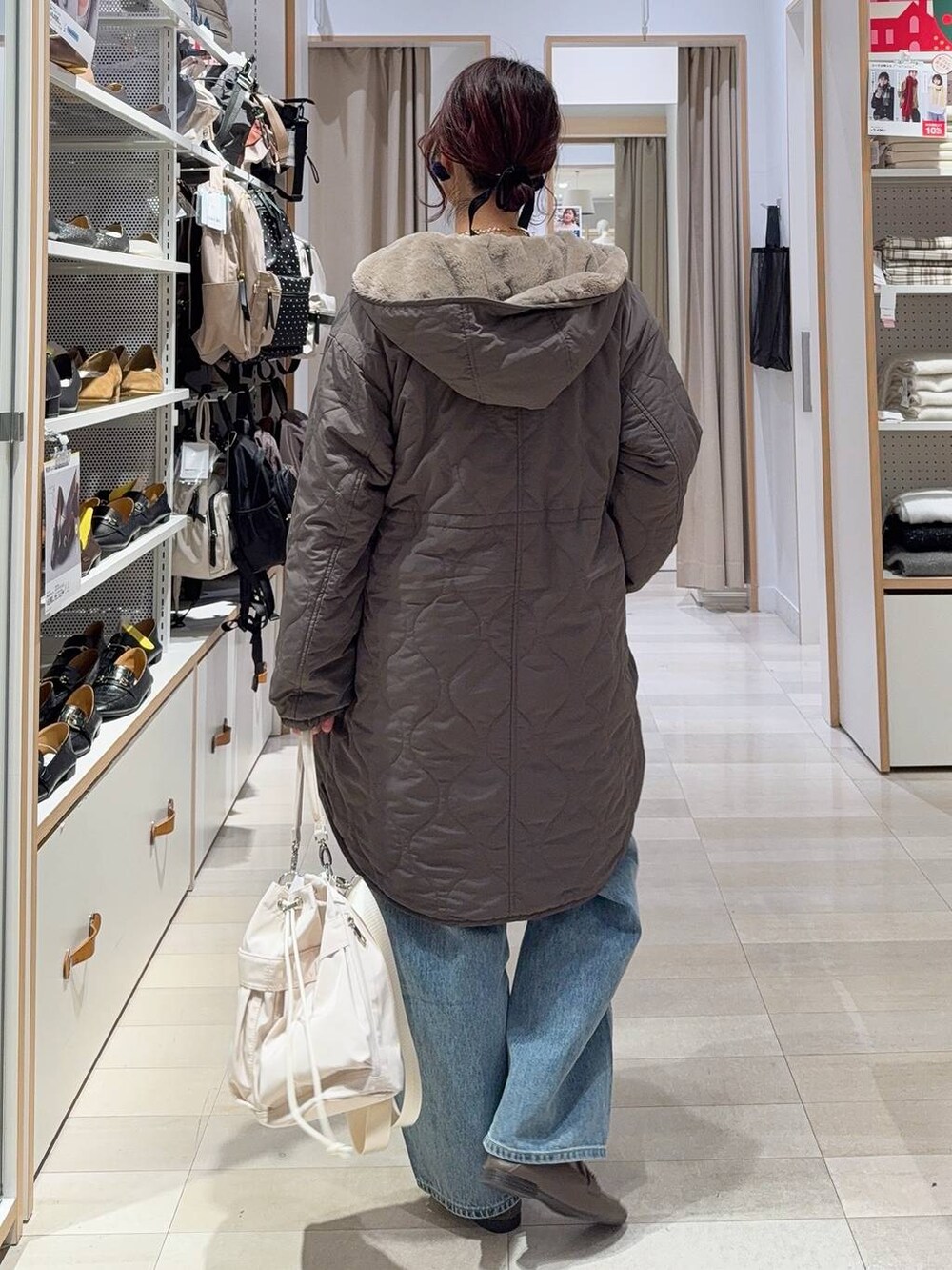 ホワイト系のショルダーバッグ、ブルー系のデニムパンツ、ブラウン系のブルゾンを着用したレディースの冬コーディネートの4枚目の写真