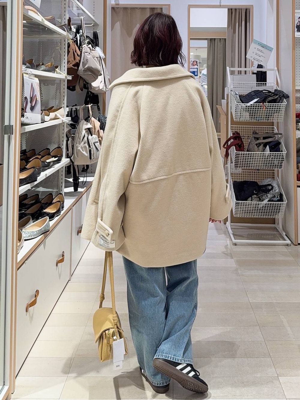 ブルー系のデニムパンツ、イエロー系のショルダーバッグ、ホワイト系のステンカラーコートを着用したレディースの冬コーディネートの6枚目の写真