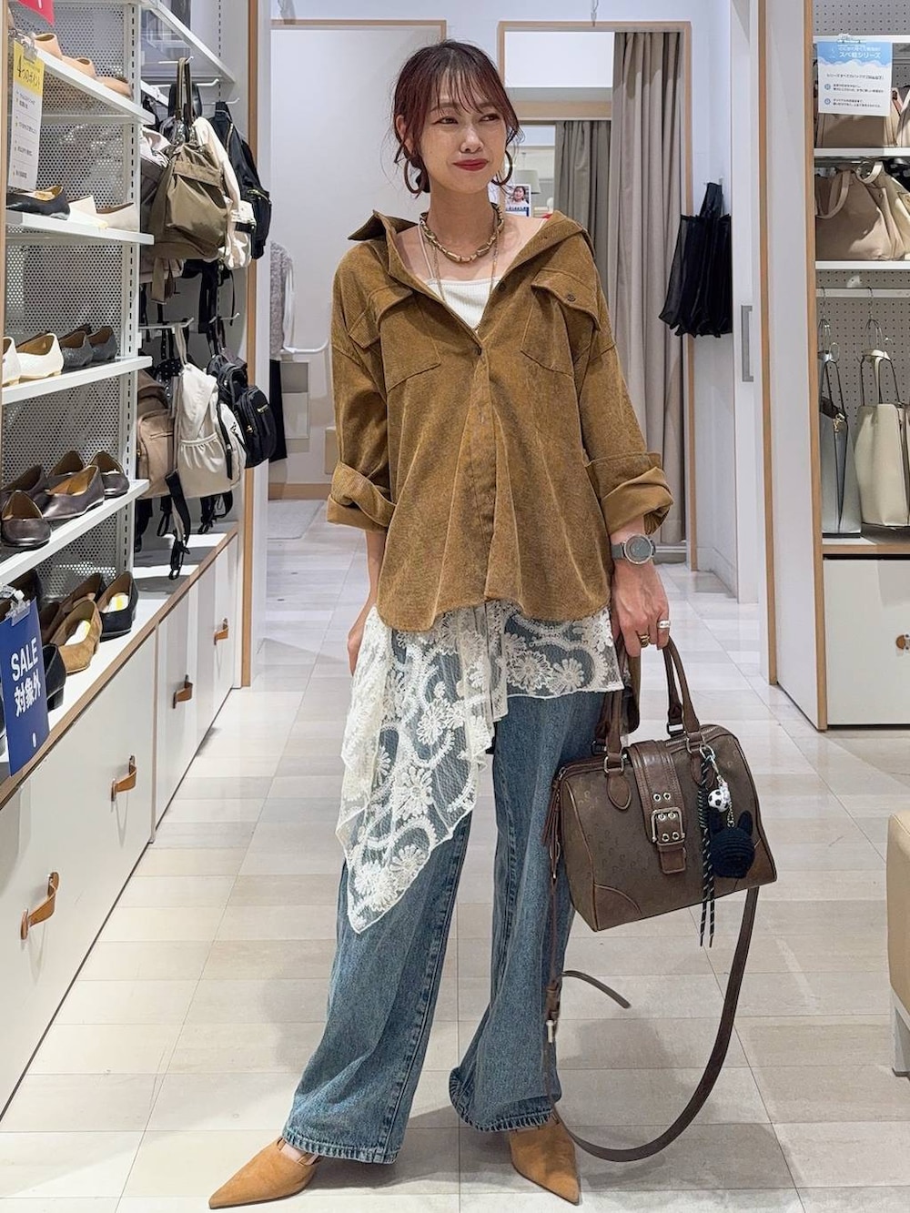 グリーン系のボストンバッグ、ベージュ系のキャミソール、ブルー系のデニムパンツを着用したレディースの秋コーディネートの4枚目の写真