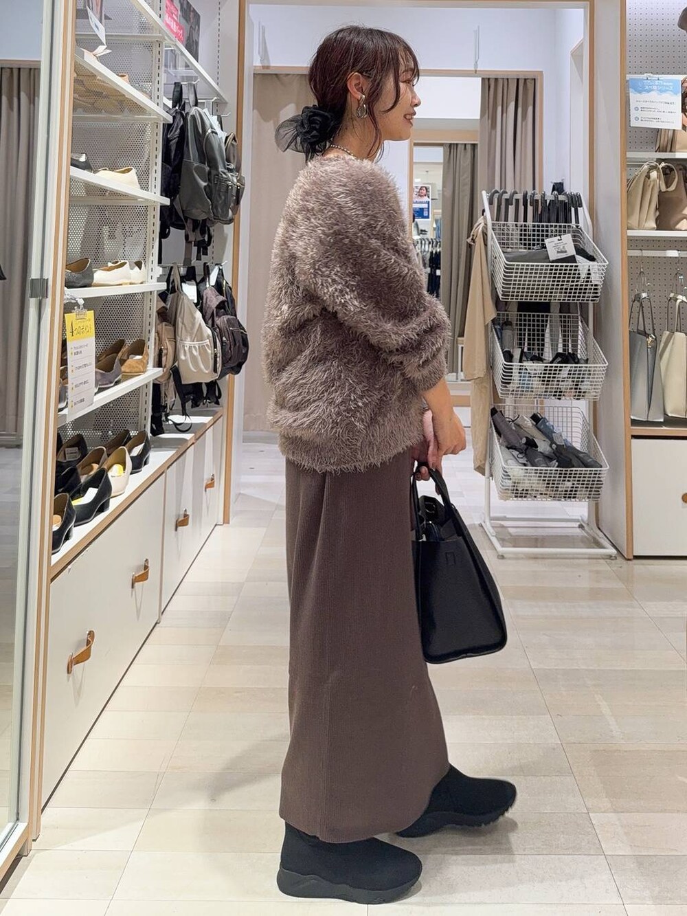 ブラック系のパンプス、ブラック系のボストンバッグ、ブルー系のデニムパンツを着用したレディースの秋コーディネートの6枚目の写真