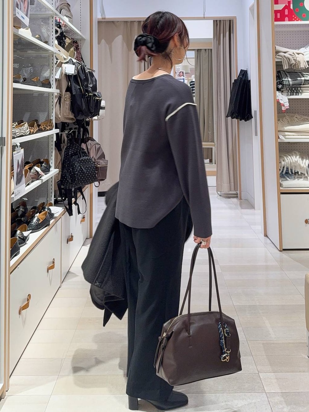 ブラウン系のボストンバッグ、ブラック系のチェスターコート、グレー系のその他パンツを着用したレディースの冬コーディネートの8枚目の写真