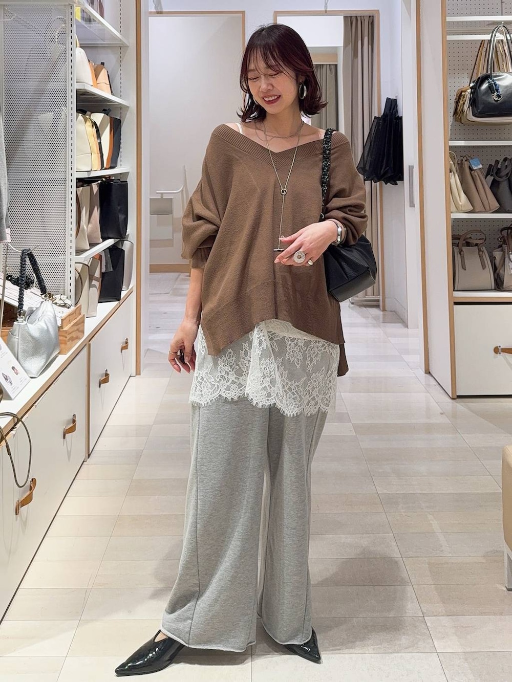 ホワイト系のキャミソール、ブラウン系のニット/セーター、グレー系のスウェットパンツを着用したレディースの冬コーディネートの3枚目の写真