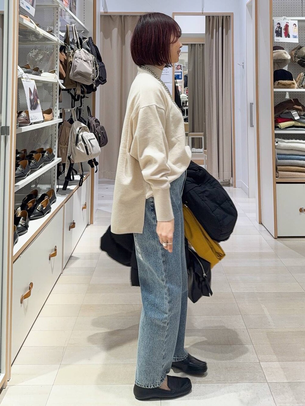 ブラック系のボストンバッグ、ブラック系のダウンジャケット/コート、ブルー系のデニムパンツを着用したレディースの秋コーディネートの7枚目の写真