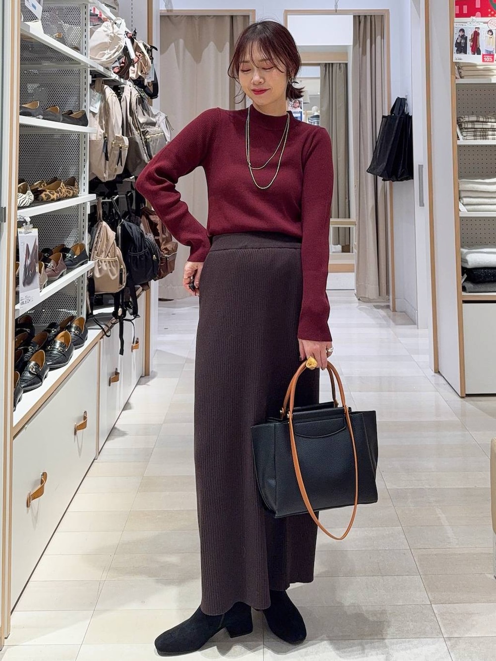 レッド系のトートバッグ、ブラック系のダウンジャケット/コート、レッド系のニット/セーターを着用したレディースの冬コーディネートの3枚目の写真