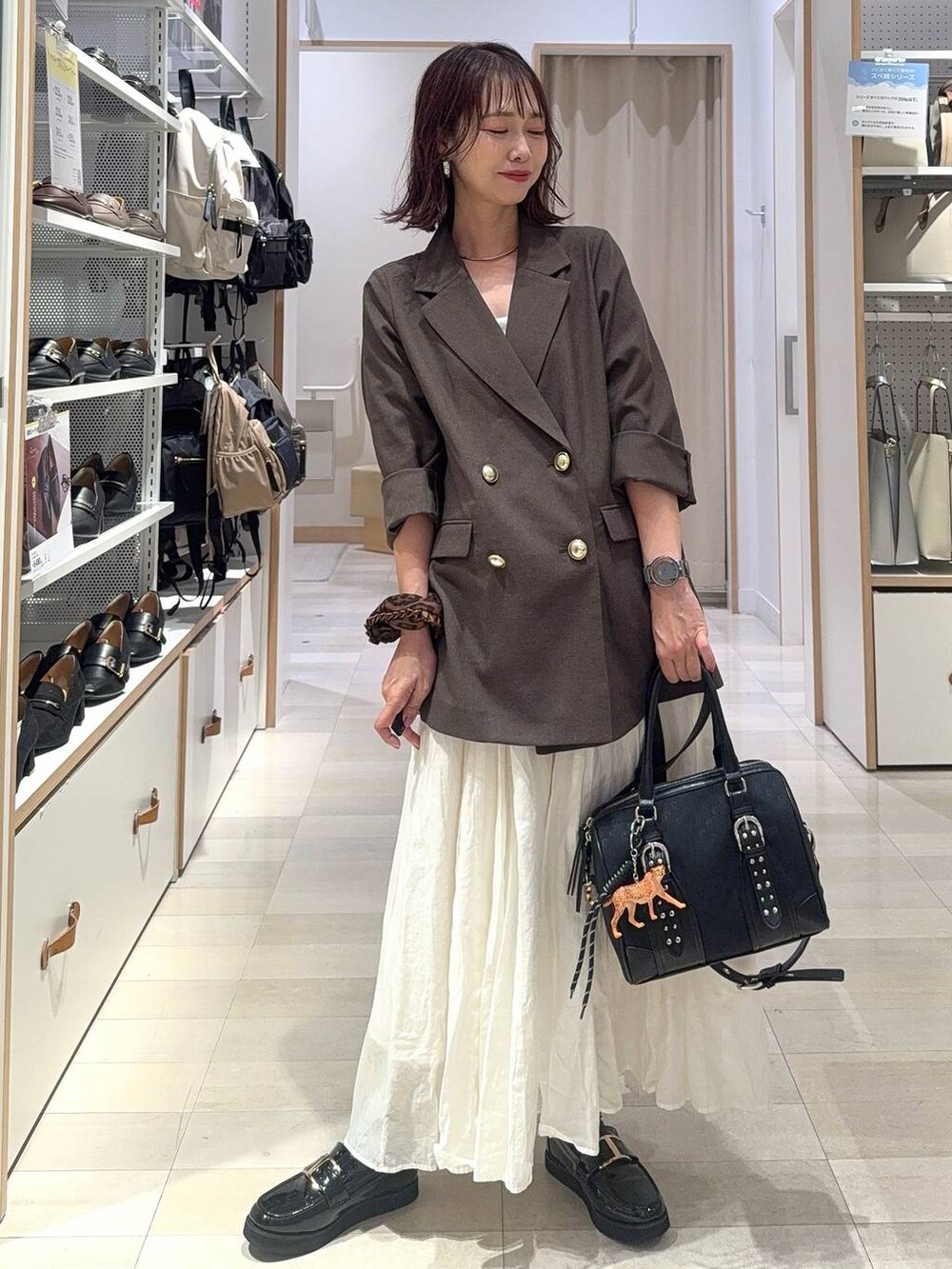 ブラック系のローファー、ホワイト系のキャミソール、ブラウン系のテーラードジャケットを着用したレディースの秋コーディネートの3枚目の写真