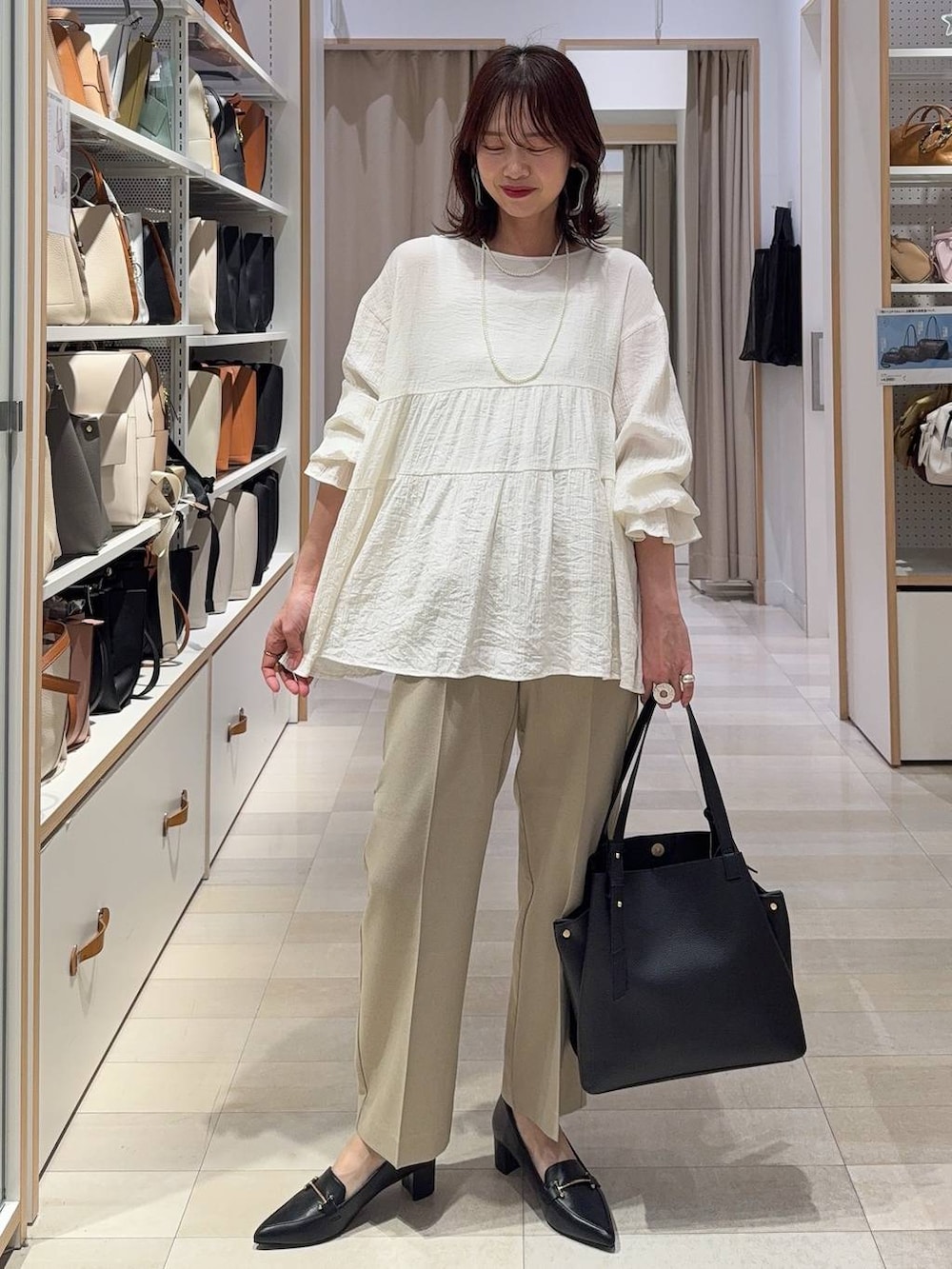 ベージュ系のその他パンツ、ベージュ系のベスト、ブラック系のハンドバッグを着用したレディースの春コーディネートの2枚目の写真