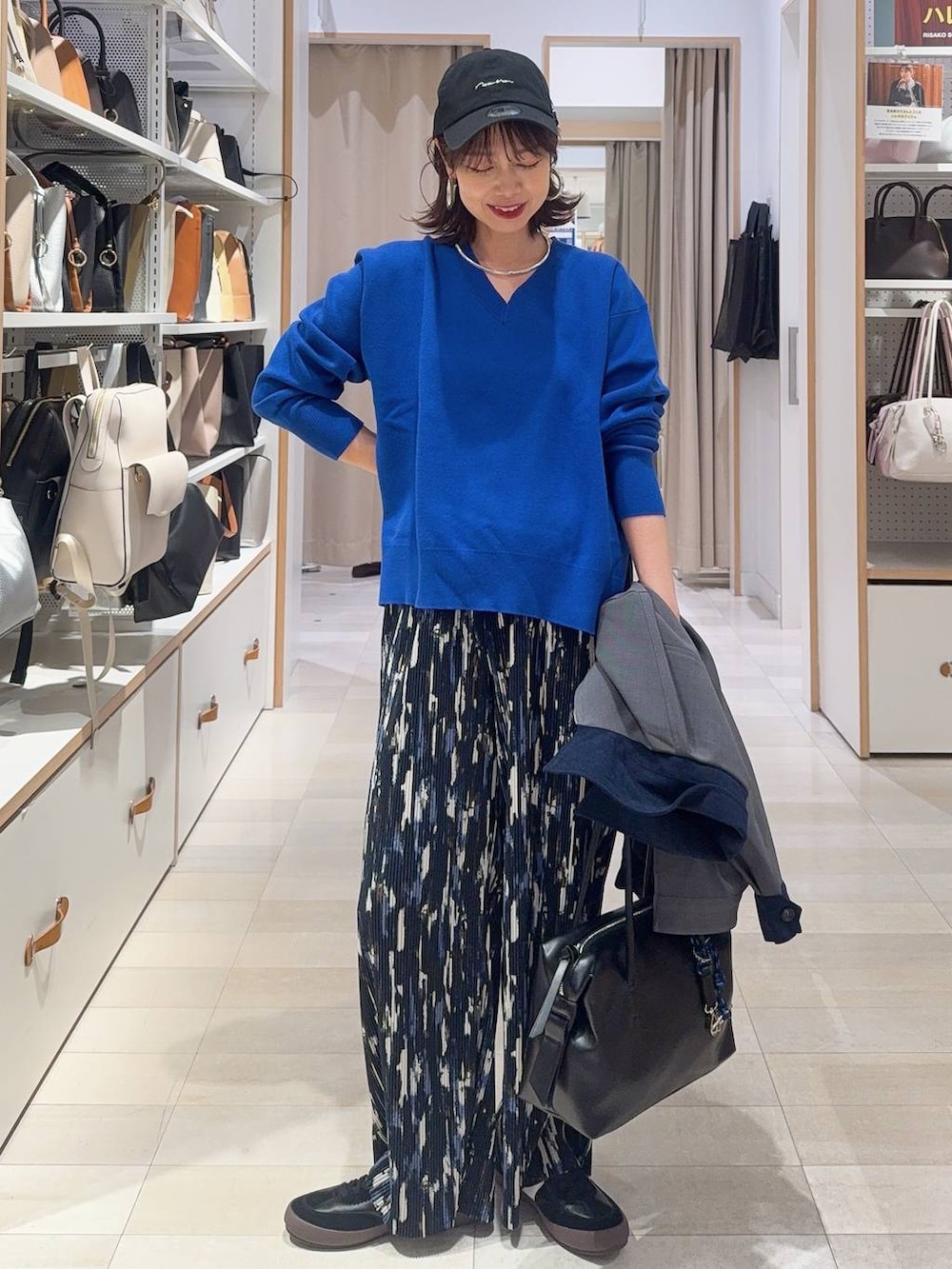 ブラック系のスニーカー、ブラック系のボストンバッグ、ブルー系のニット/セーターを着用したレディースの冬コーディネートの2枚目の写真