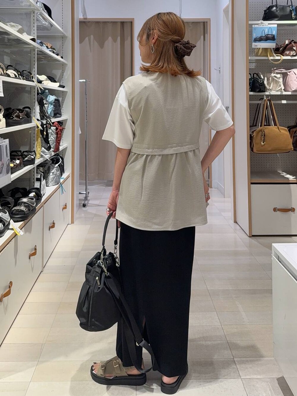 ブラック系のショルダーバッグ、ベージュ系のベスト、ホワイト系のTシャツ/カットソーを着用したレディースの夏コーディネートの6枚目の写真