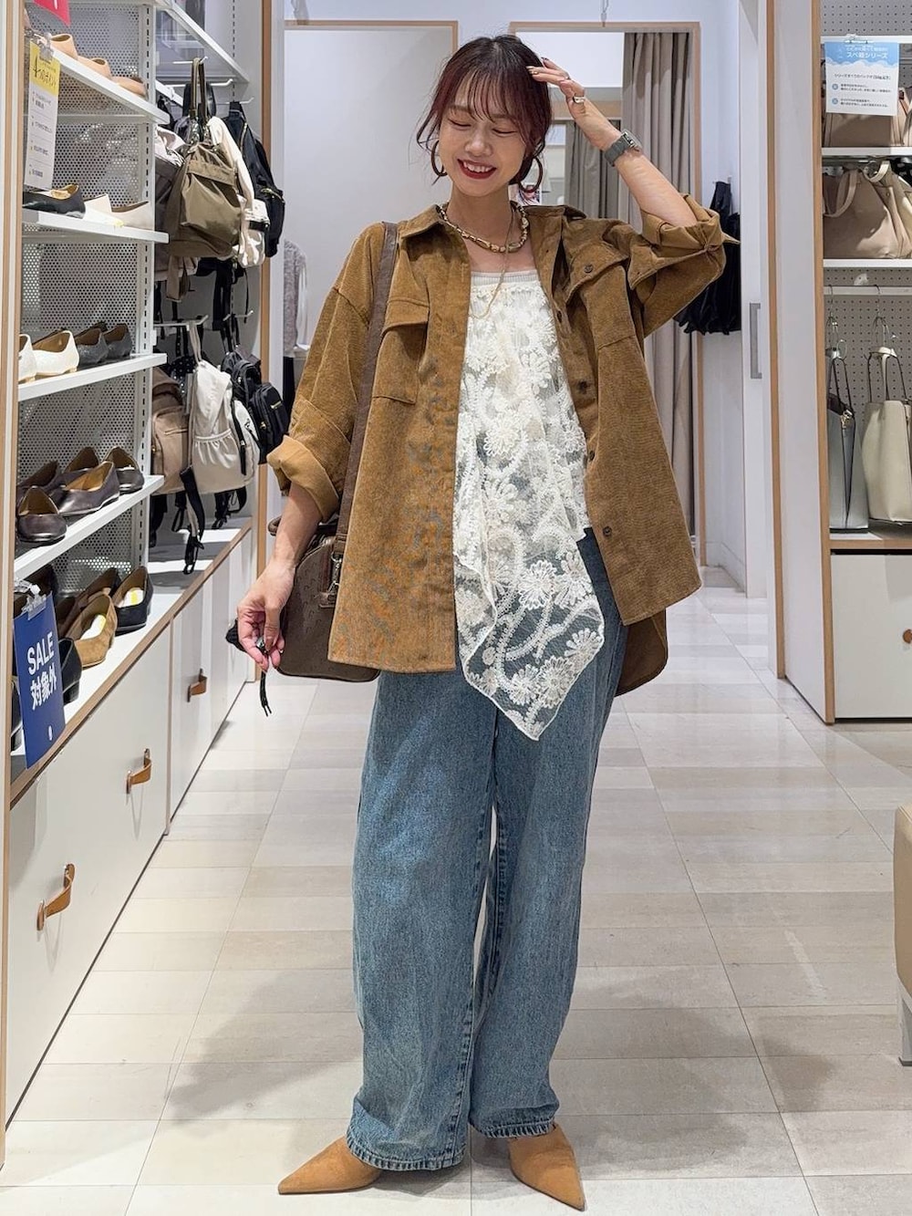 グリーン系のボストンバッグ、ベージュ系のキャミソール、ブルー系のデニムパンツを着用したレディースの秋コーディネートの3枚目の写真