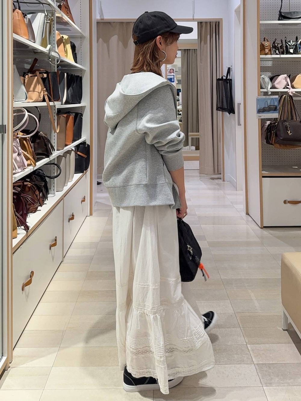 ブラック系のボストンバッグ、グレー系のパーカー、ホワイト系のスカートを着用したレディースの春コーディネートの5枚目の写真