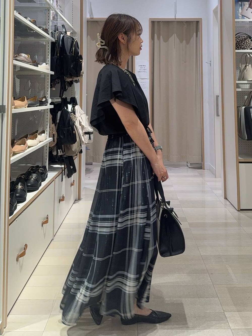 ブルー系のスカート、ホワイト系のショルダーバッグ、ブラック系のTシャツ/カットソーを着用したレディースの夏コーディネートの2枚目の写真