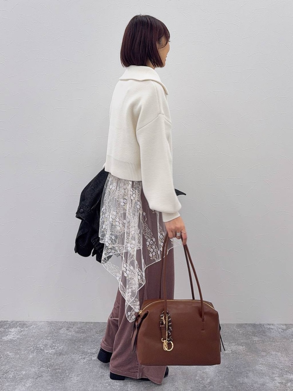 ブラウン系のボストンバッグ、ブラック系のブーツ、ホワイト系のその他トップスを着用したレディースの秋コーディネートの6枚目の写真