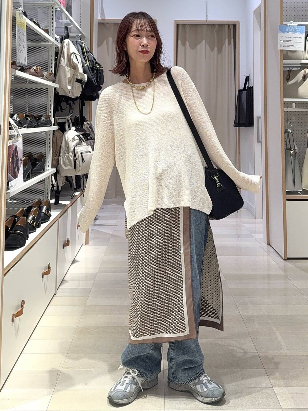 ホワイト系のキャミソール、ブルー系のデニムパンツ、ブラック系のボストンバッグを着用したレディースの秋コーディネートの3枚目の写真