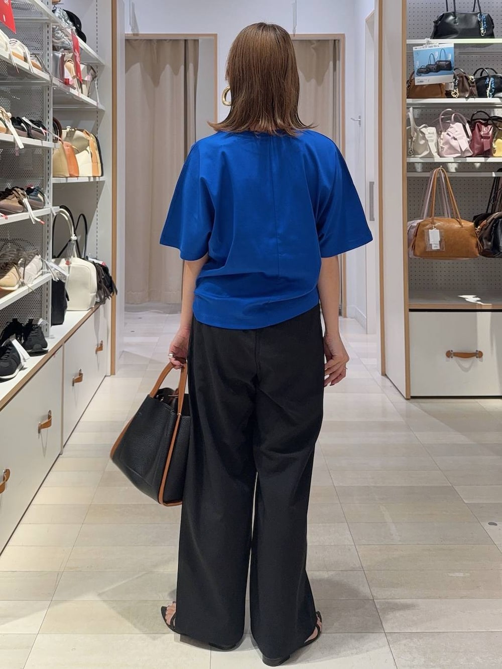 ブラック系のトートバッグ、ブラック系のその他パンツ、ブルー系のTシャツ/カットソーを着用したレディースの夏コーディネートの4枚目の写真