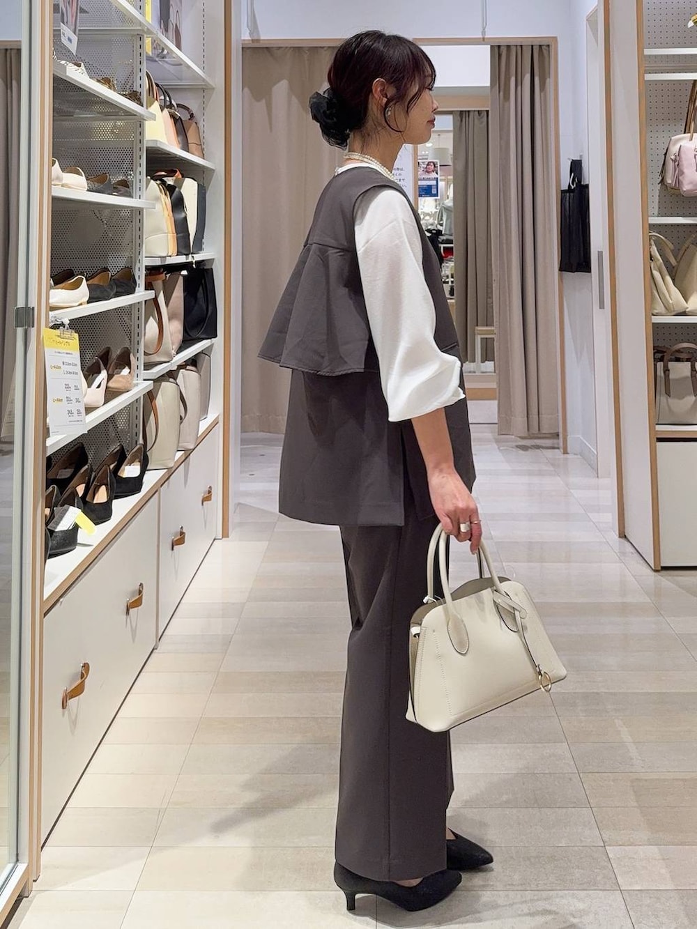 ホワイト系のショルダーバッグ、ブラック系のパンプス、グレー系のセットアップを着用したレディースの冬コーディネートの3枚目の写真