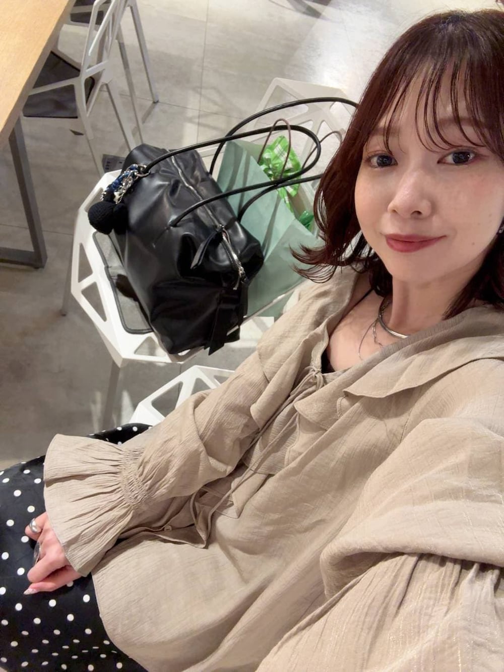 ホワイト系のブルゾン、ブラック系のスカート、ブラック系のボストンバッグを着用したレディースの春コーディネートの2枚目の写真