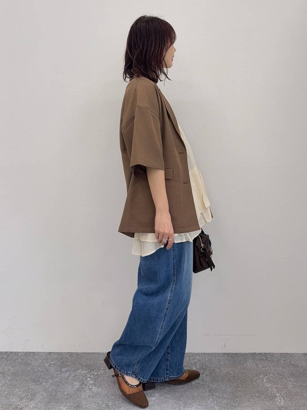 ブルー系のデニムパンツ、ブラウン系のキャミソール、ブラウン系のボストンバッグを着用したレディースの春コーディネートの4枚目の写真