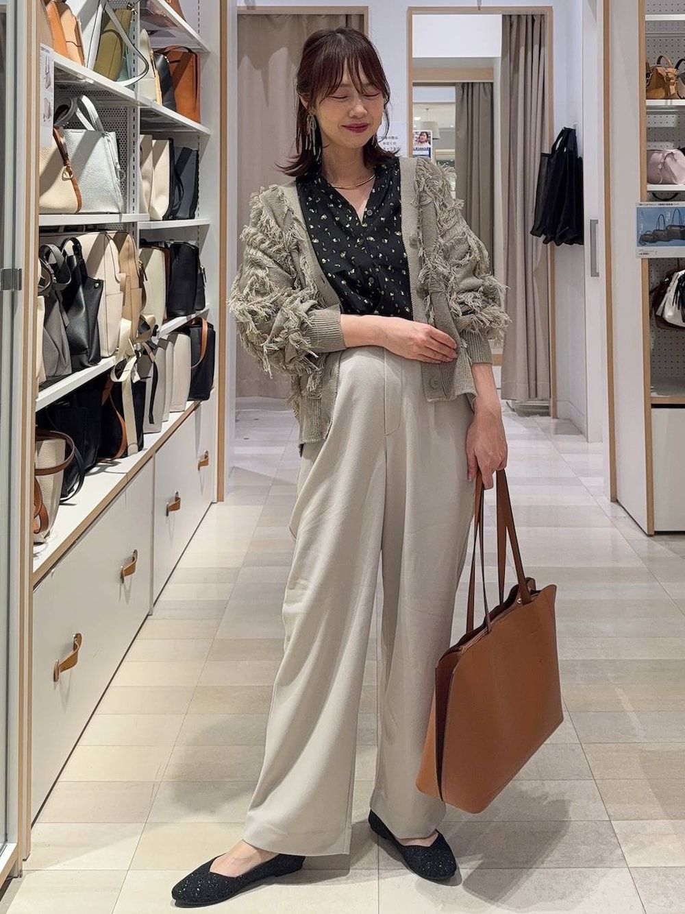 ブラック系のシャツ/ブラウス、ブラウン系のトートバッグ、ブラック系のパンプスを着用したレディースの春コーディネートの2枚目の写真