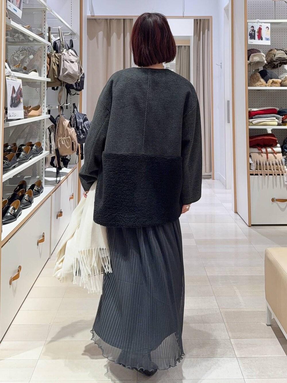 ホワイト系のショルダーバッグ、グレー系のノーカラージャケット、ブラック系のブーツを着用したレディースの秋コーディネートの5枚目の写真