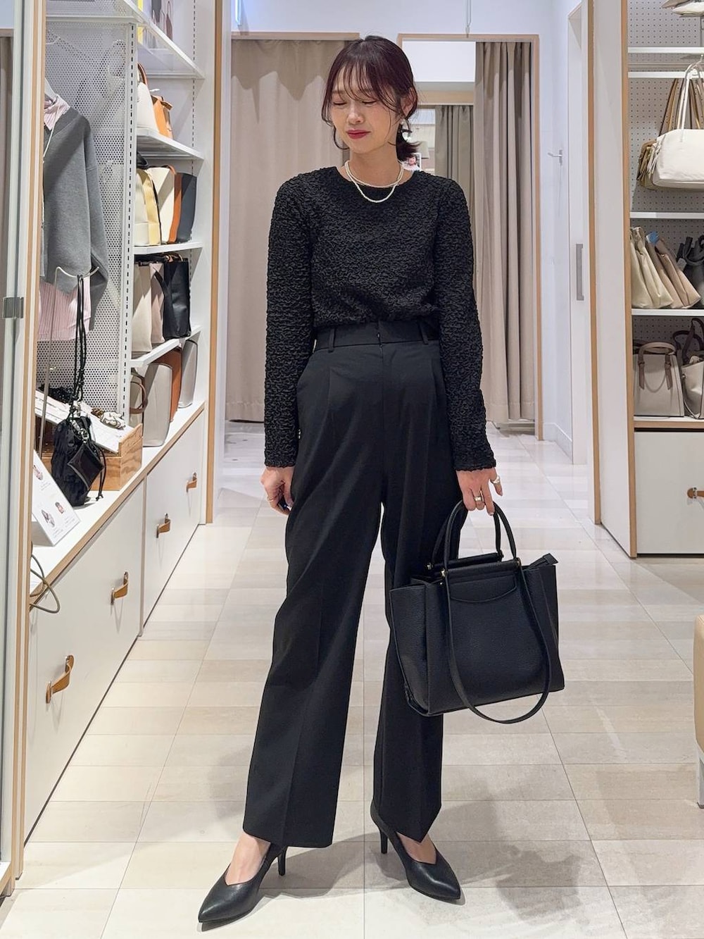 ブラック系のスラックス、ブラック系のトートバッグ、ブラウン系のテーラードジャケットを着用したレディースの冬コーディネートの2枚目の写真