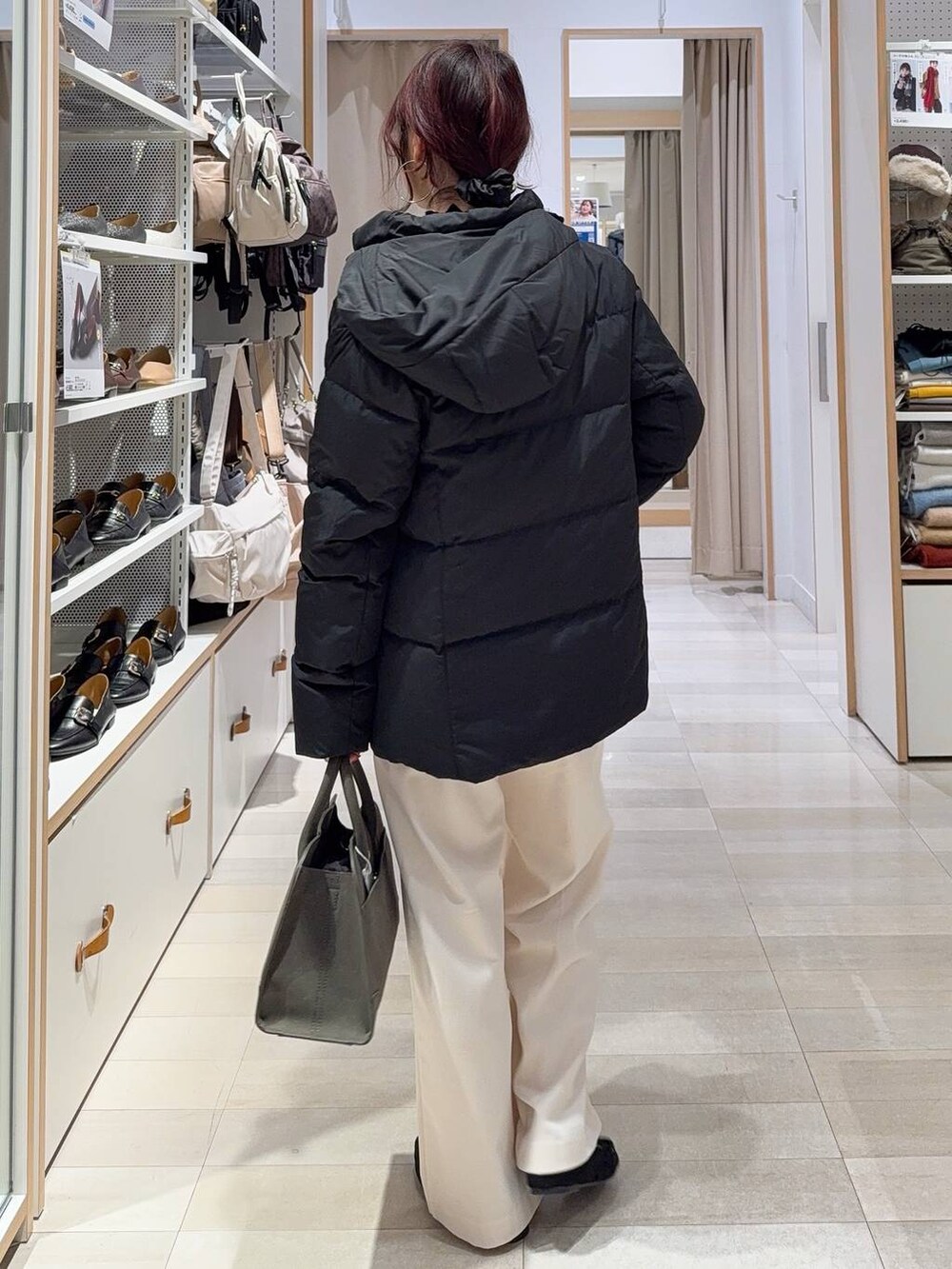 ブラック系のダウンジャケット/コート、グリーン系のショルダーバッグ、ブラック系のニット/セーターを着用したレディースの秋コーディネートの7枚目の写真