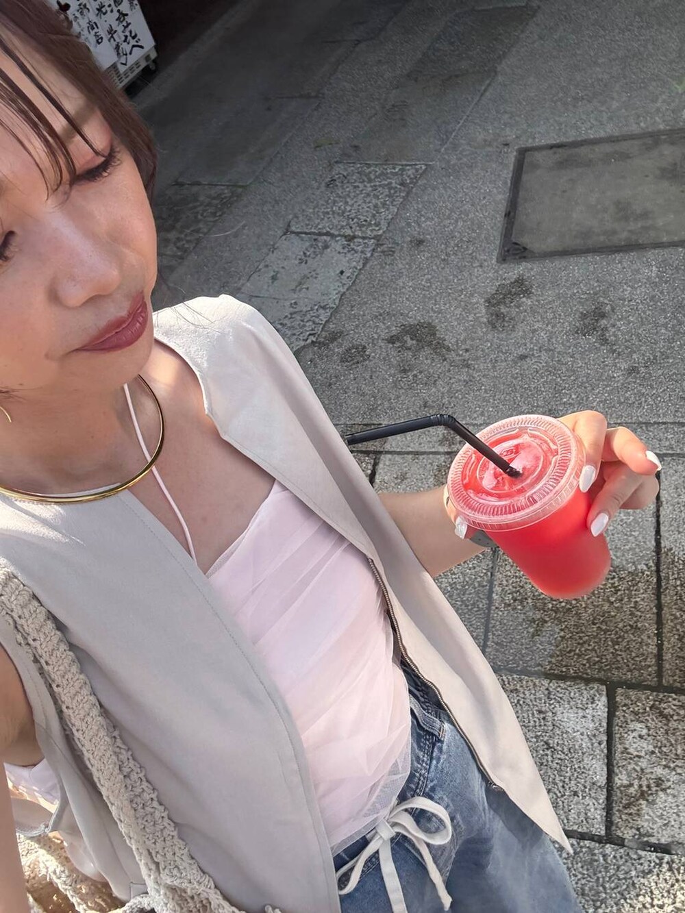 ブルー系のデニムパンツ、ベージュ系のベスト、シルバー系のネックレスを着用したレディースの夏コーディネートの3枚目の写真