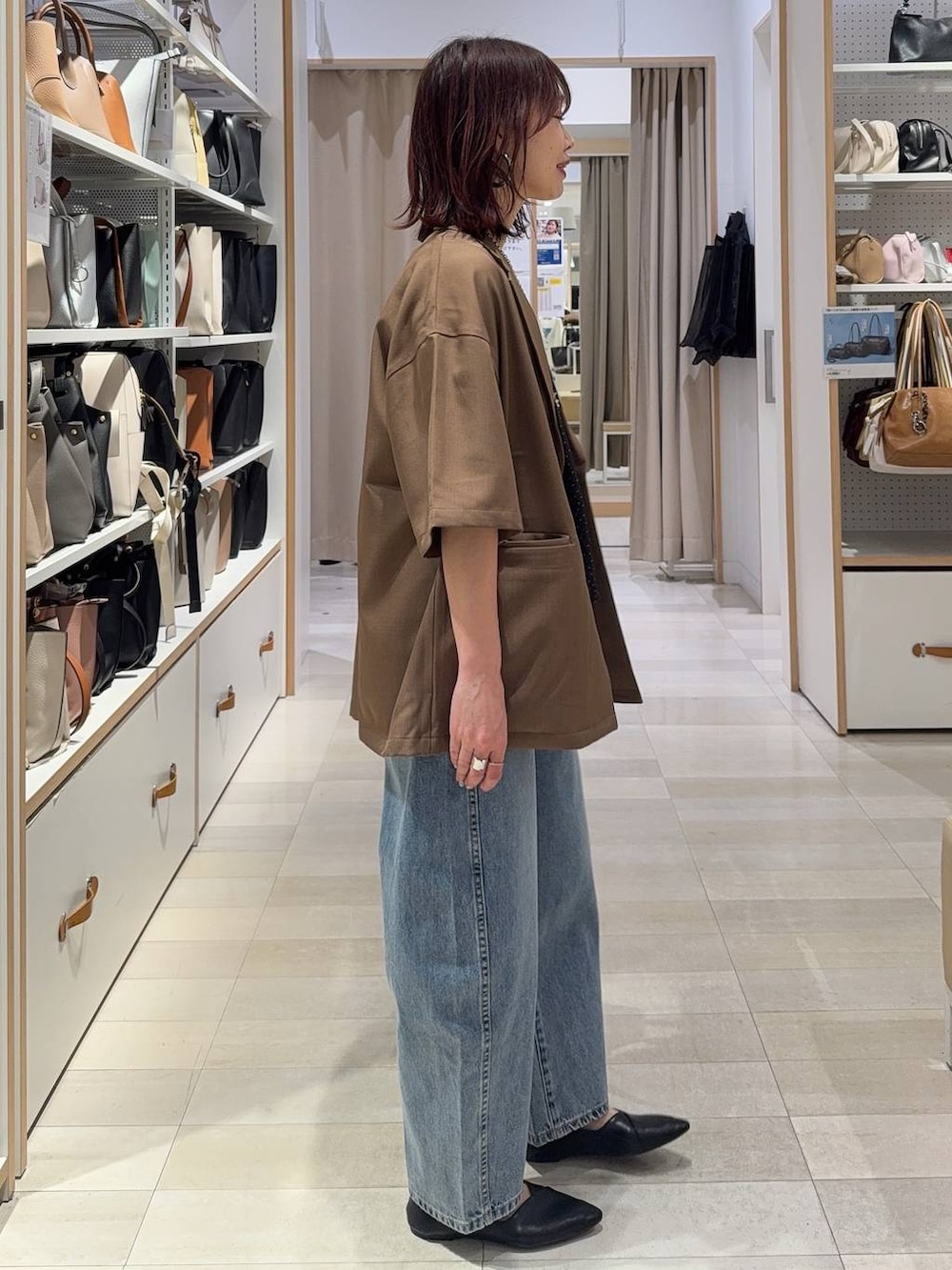 ブラック系のパンプス、ブルー系のデニムパンツ、シルバー系のネックレスを着用したレディースの春コーディネートの5枚目の写真