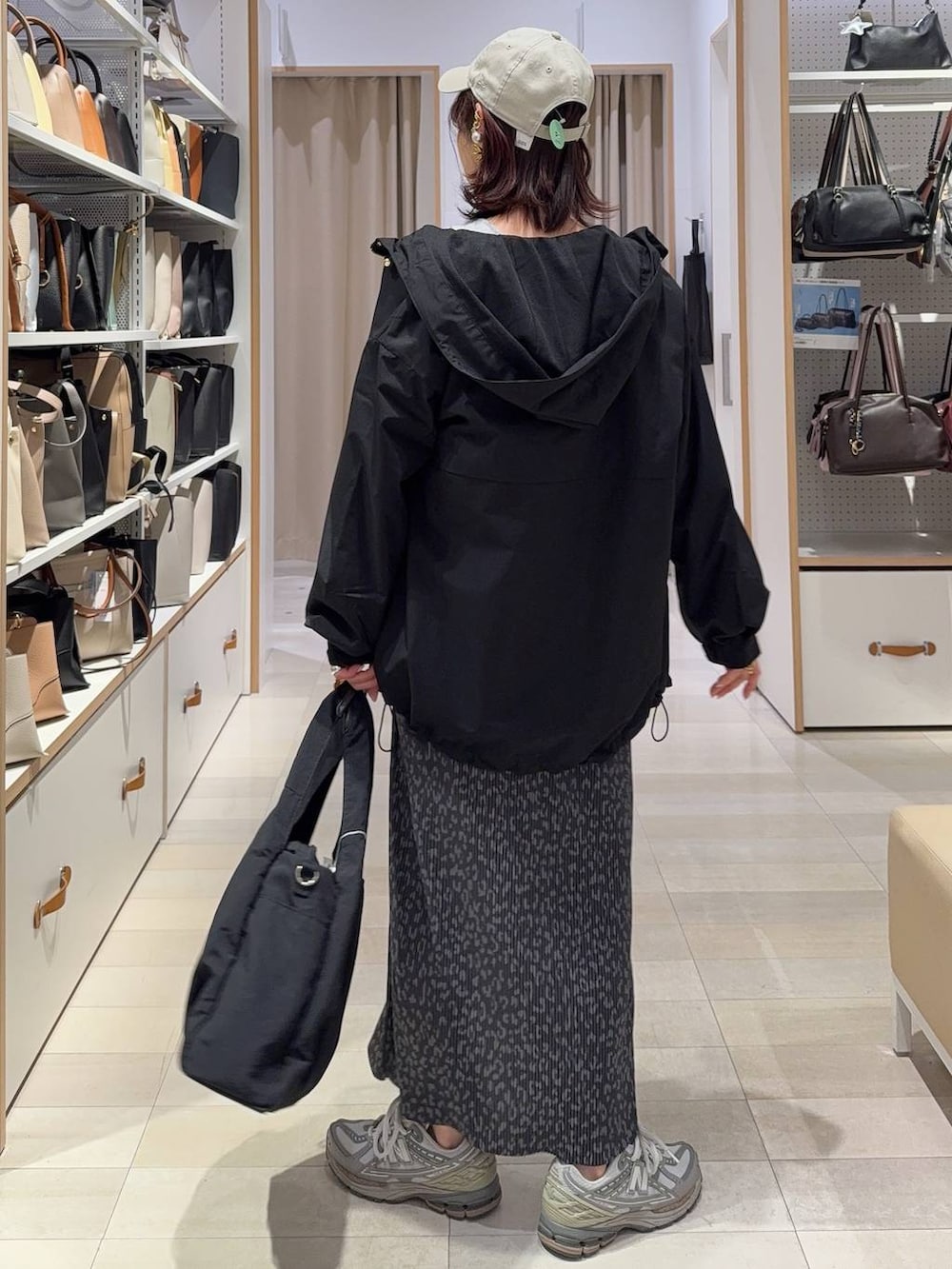 ブラック系のトートバッグ、ブラック系のマウンテンパーカー、グレー系のスカートを着用したレディースの春コーディネートの5枚目の写真