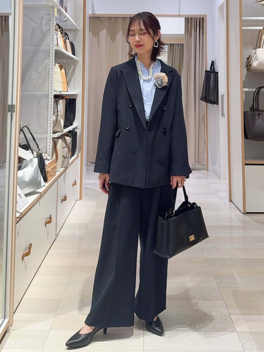 ブラック系のボストンバッグ、ブラック系のスニーカー、ブルー系のテーラードジャケットを着用したレディースの冬コーディネートの5枚目の写真