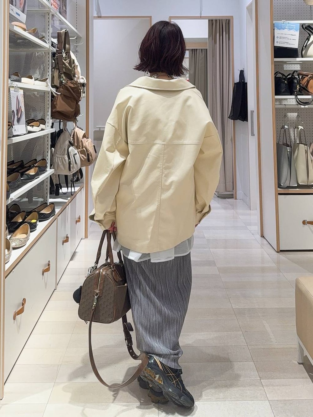 グリーン系のボストンバッグ、ホワイト系のブルゾン、グレー系のスカートを着用したレディースの秋コーディネートの6枚目の写真