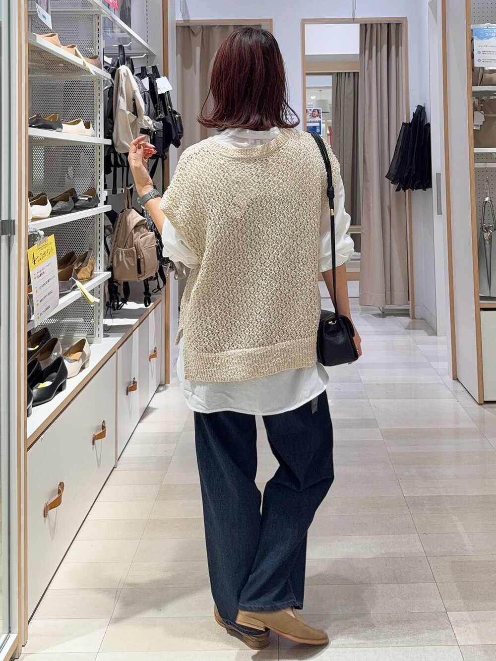 ブルー系のデニムパンツ、ベージュ系のシャツ/ブラウス、ブラック系のショルダーバッグを着用したレディースの秋コーディネートの3枚目の写真