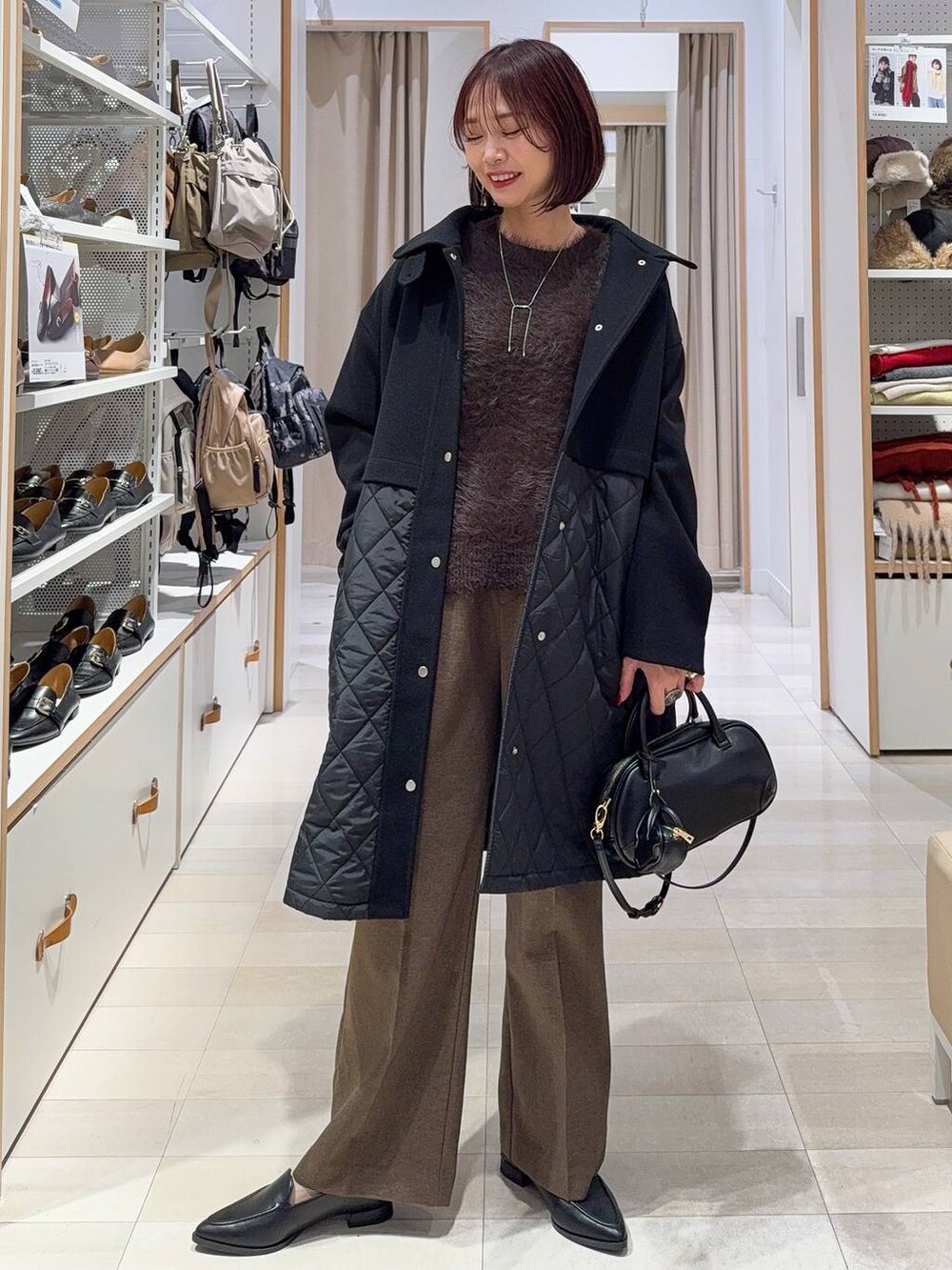 ブラック系のステンカラーコート、ブラウン系のその他パンツ、ブラック系のパンプスを着用したレディースの秋コーディネートの2枚目の写真