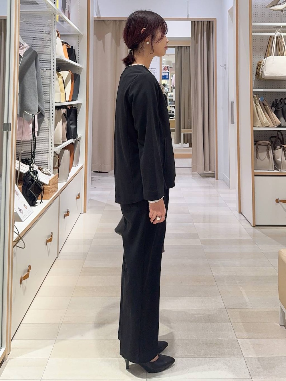 ブラック系のショルダーバッグ、ホワイト系のパンプス、ブラック系のセットアップを着用したレディースの冬コーディネートの3枚目の写真