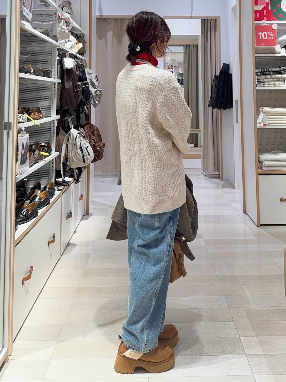 ブラウン系のボストンバッグ、ブルー系のデニムパンツ、ブラウン系のチェスターコートを着用したレディースの冬コーディネートの7枚目の写真