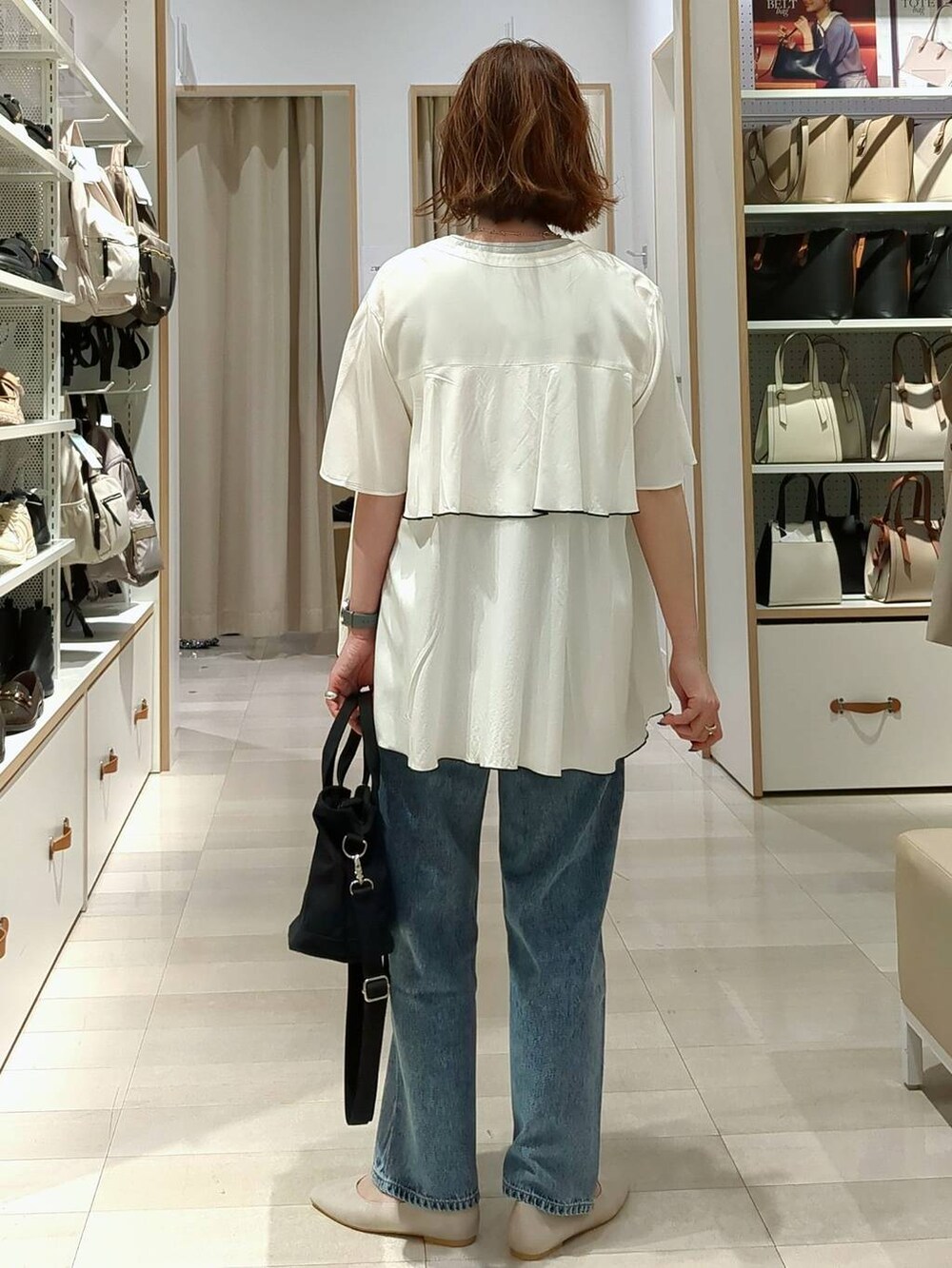 ベージュ系のパンプス、ブルー系のデニムパンツ、ブラック系のトートバッグを着用したレディースの春コーディネートの4枚目の写真