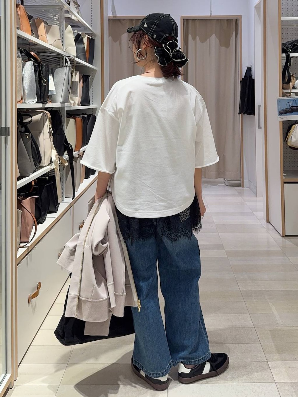 ブラック系のスニーカー、ブルー系のデニムパンツ、ベージュ系のパーカーを着用したレディースの春コーディネートの7枚目の写真