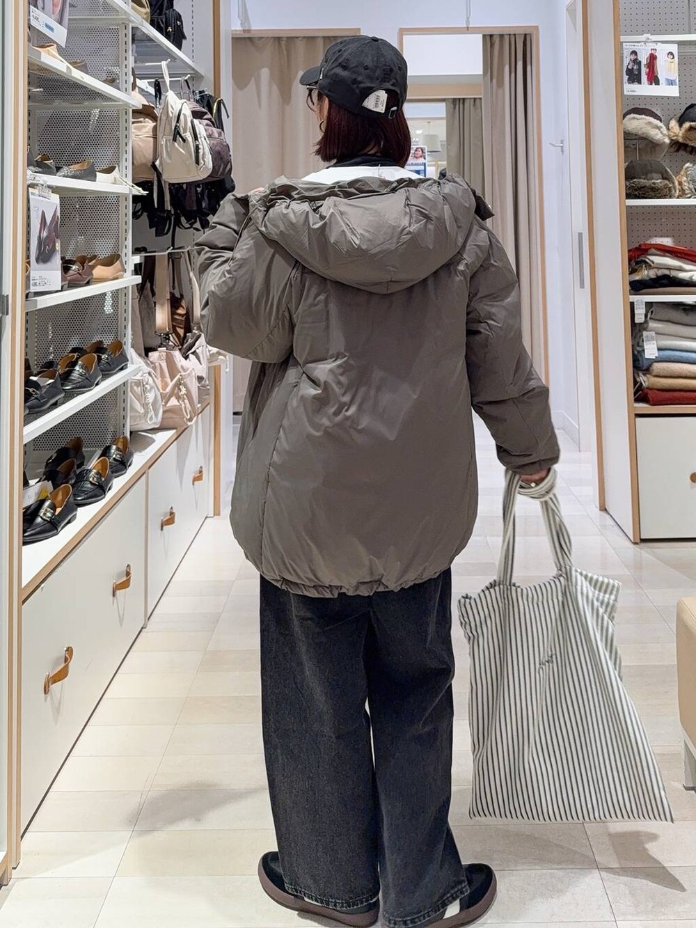 ブラック系のスニーカー、ブラウン系のダウンジャケット/コート、ブラック系のデニムパンツを着用したレディースの秋コーディネートの6枚目の写真