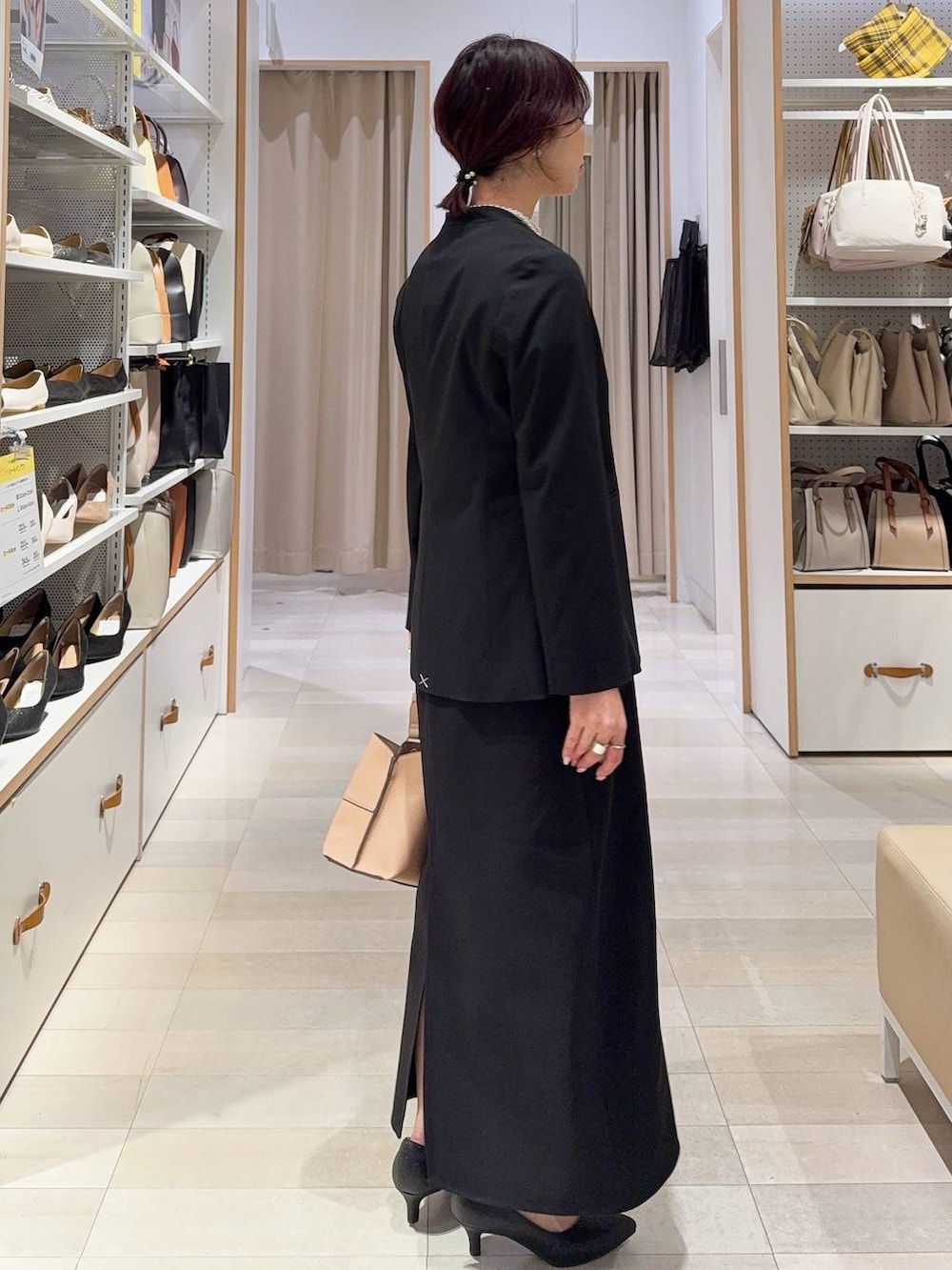 ブラック系のパンプス、ブラック系のノーカラージャケット、ベージュ系のショルダーバッグを着用したレディースの冬コーディネートの4枚目の写真