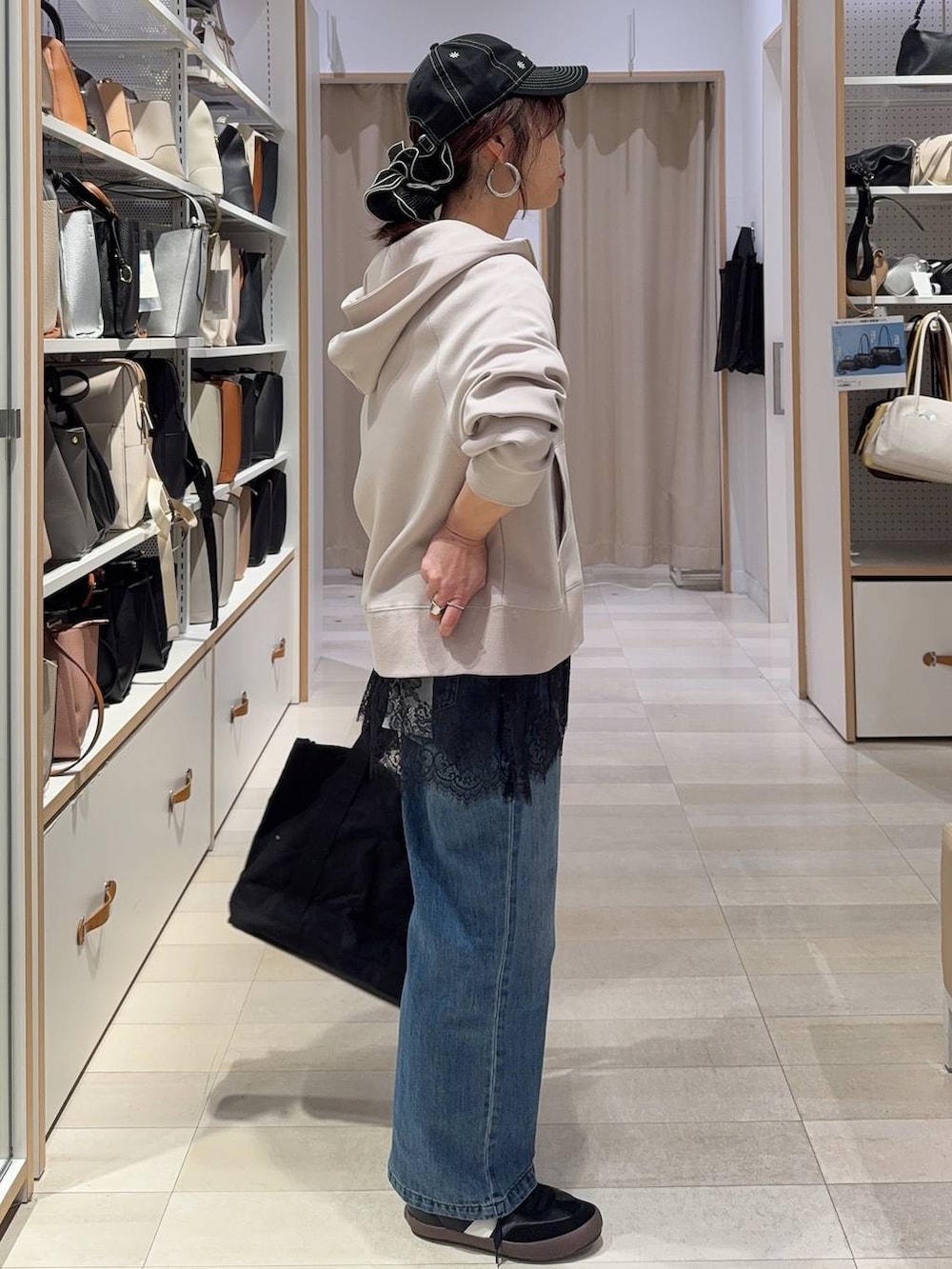 ブラック系のスニーカー、ブルー系のデニムパンツ、ベージュ系のパーカーを着用したレディースの春コーディネートの4枚目の写真