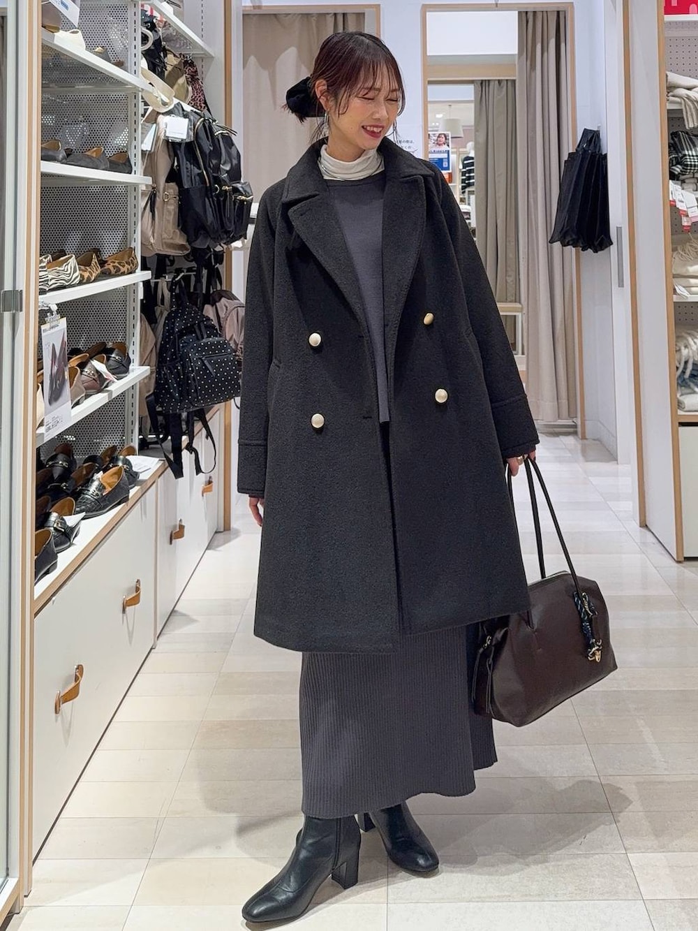 ブラウン系のボストンバッグ、ブラック系のチェスターコート、ホワイト系のTシャツ/カットソーを着用したレディースの冬コーディネートの2枚目の写真