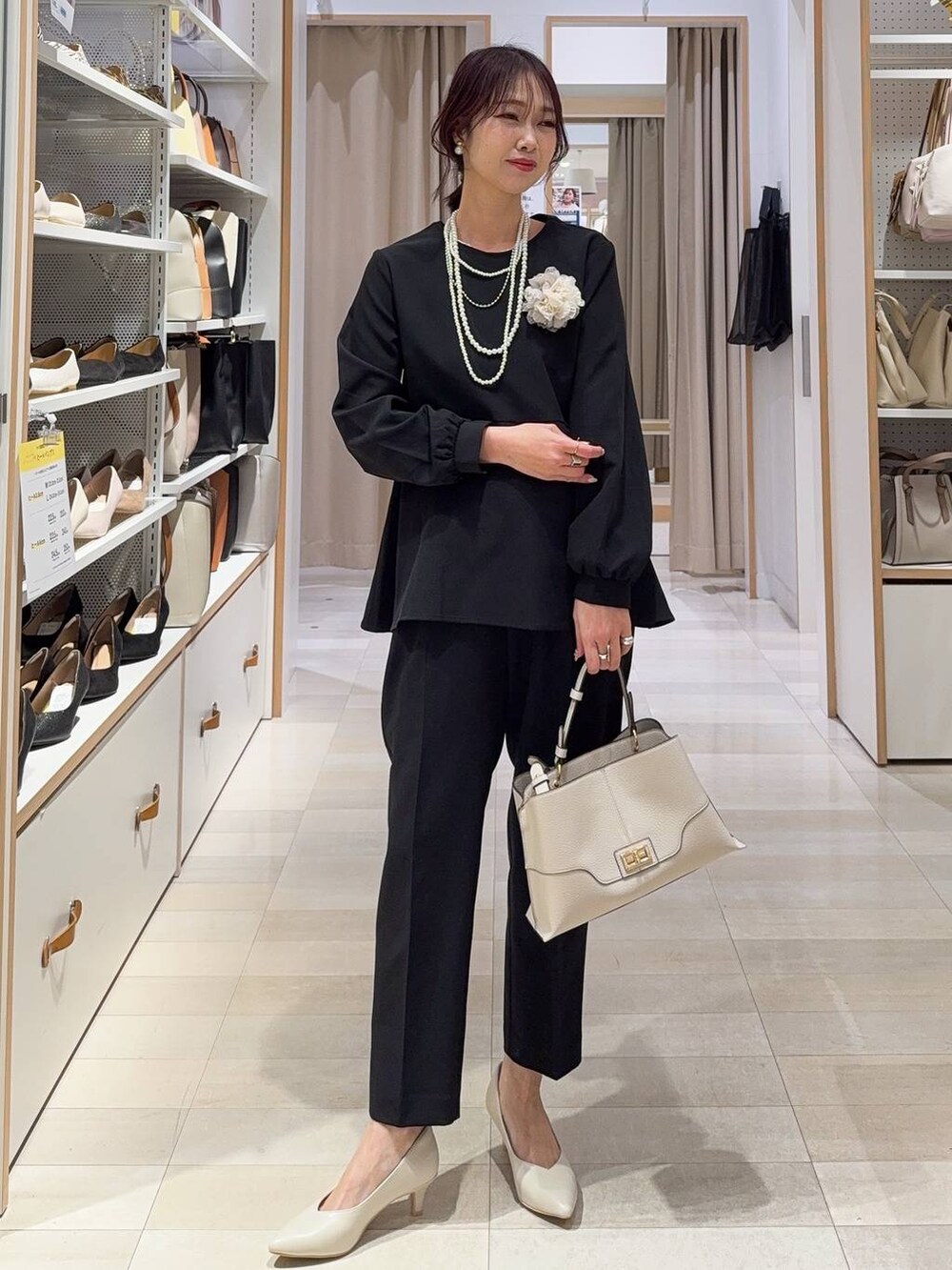ホワイト系のショルダーバッグ、ブラック系のパンプス、ブラック系のセットアップを着用したレディースの冬コーディネートの3枚目の写真