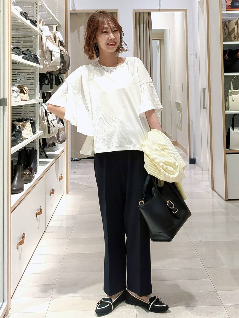 ブラック系のショルダーバッグ、イエロー系のカーディガン/ボレロ、その他のパンプスを着用したレディースの春コーディネートの2枚目の写真