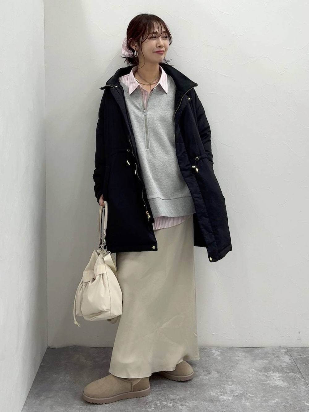 ホワイト系のショルダーバッグ、ブラック系のダウンジャケット/コート、ホワイト系のスカートを着用したレディースの冬コーディネートの2枚目の写真