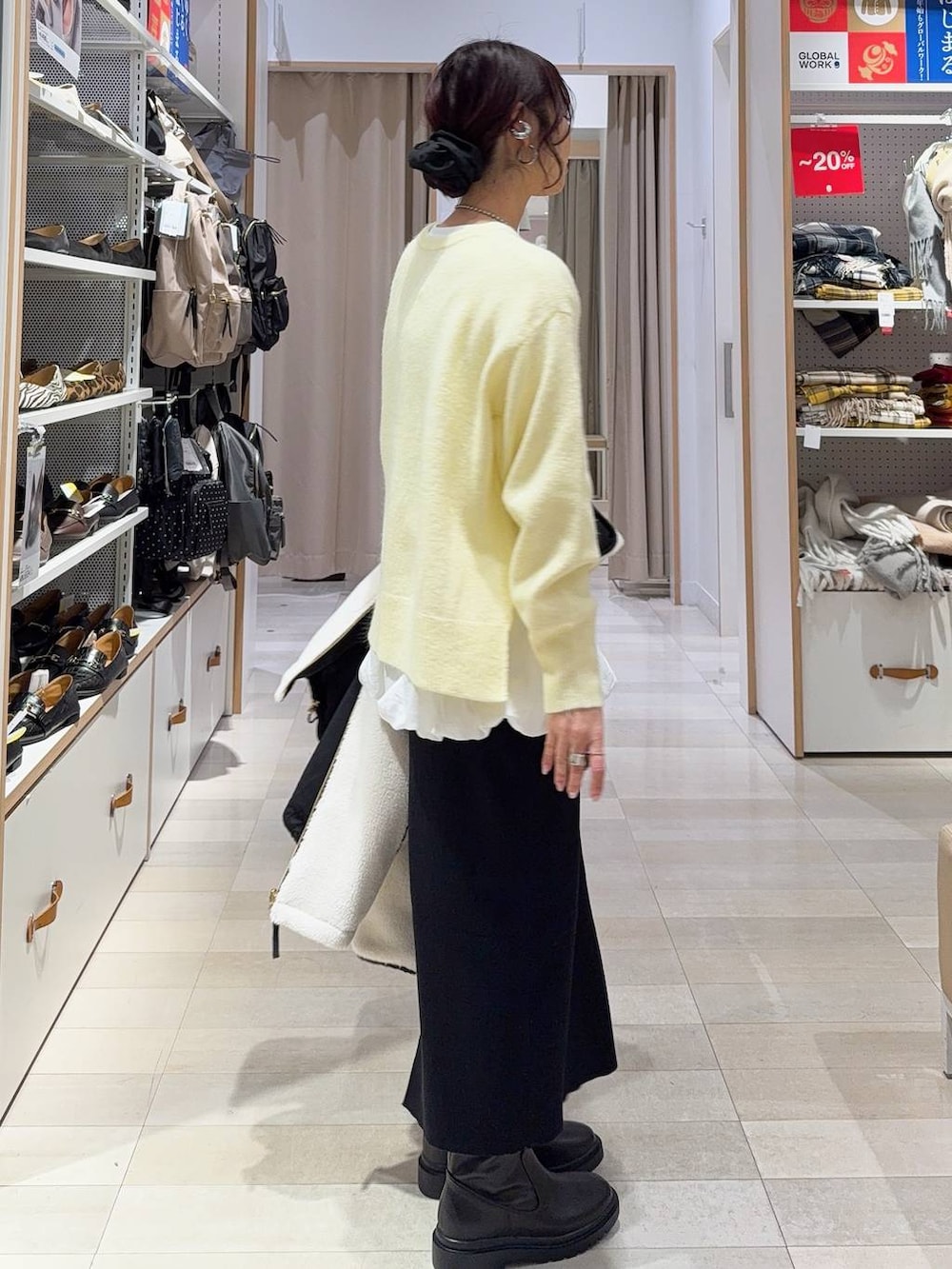 ブラック系のボストンバッグ、ホワイト系のブルゾン、イエロー系のニット/セーターを着用したレディースの冬コーディネートの7枚目の写真