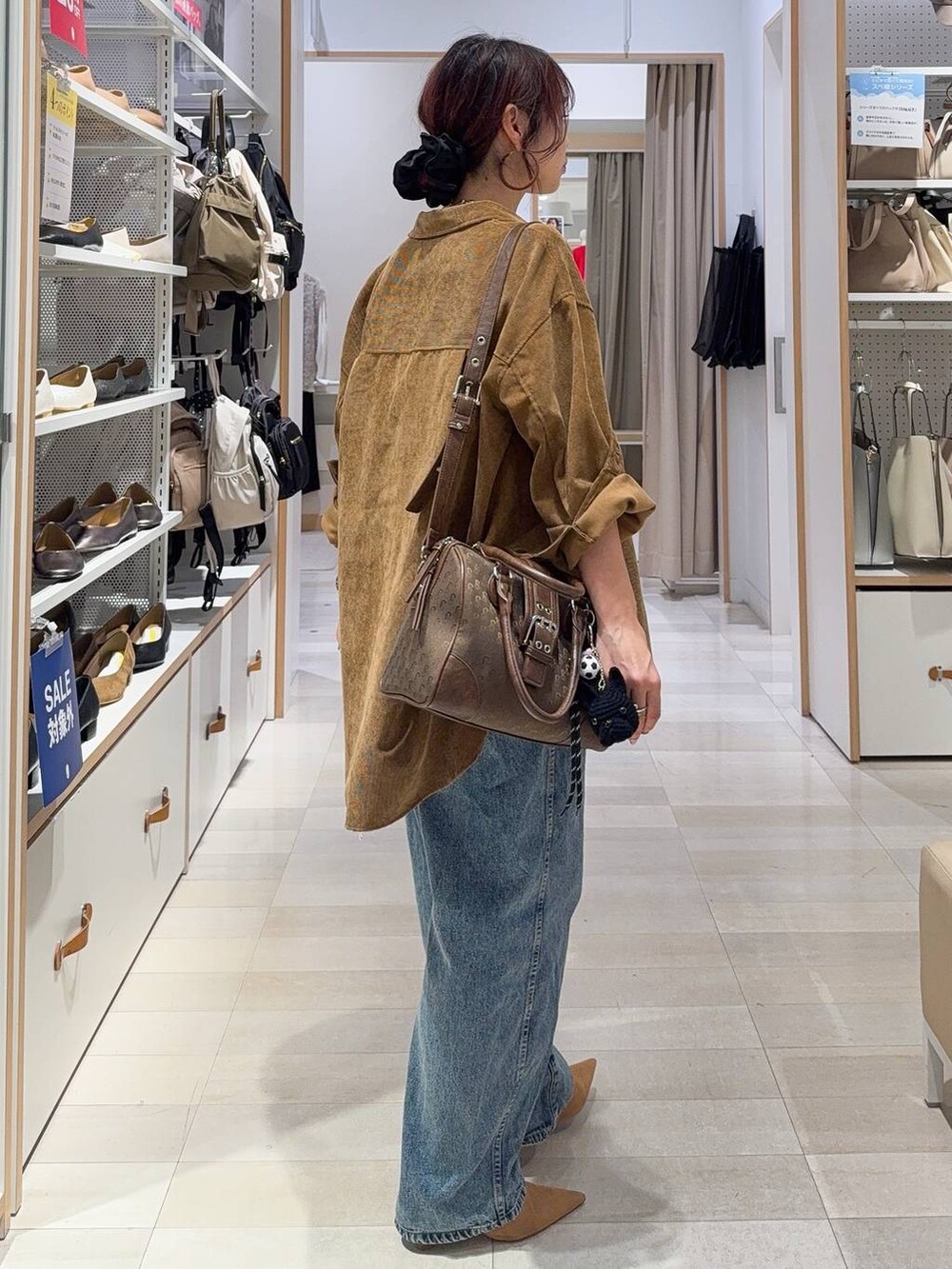 グリーン系のボストンバッグ、ベージュ系のキャミソール、ブルー系のデニムパンツを着用したレディースの秋コーディネートの5枚目の写真