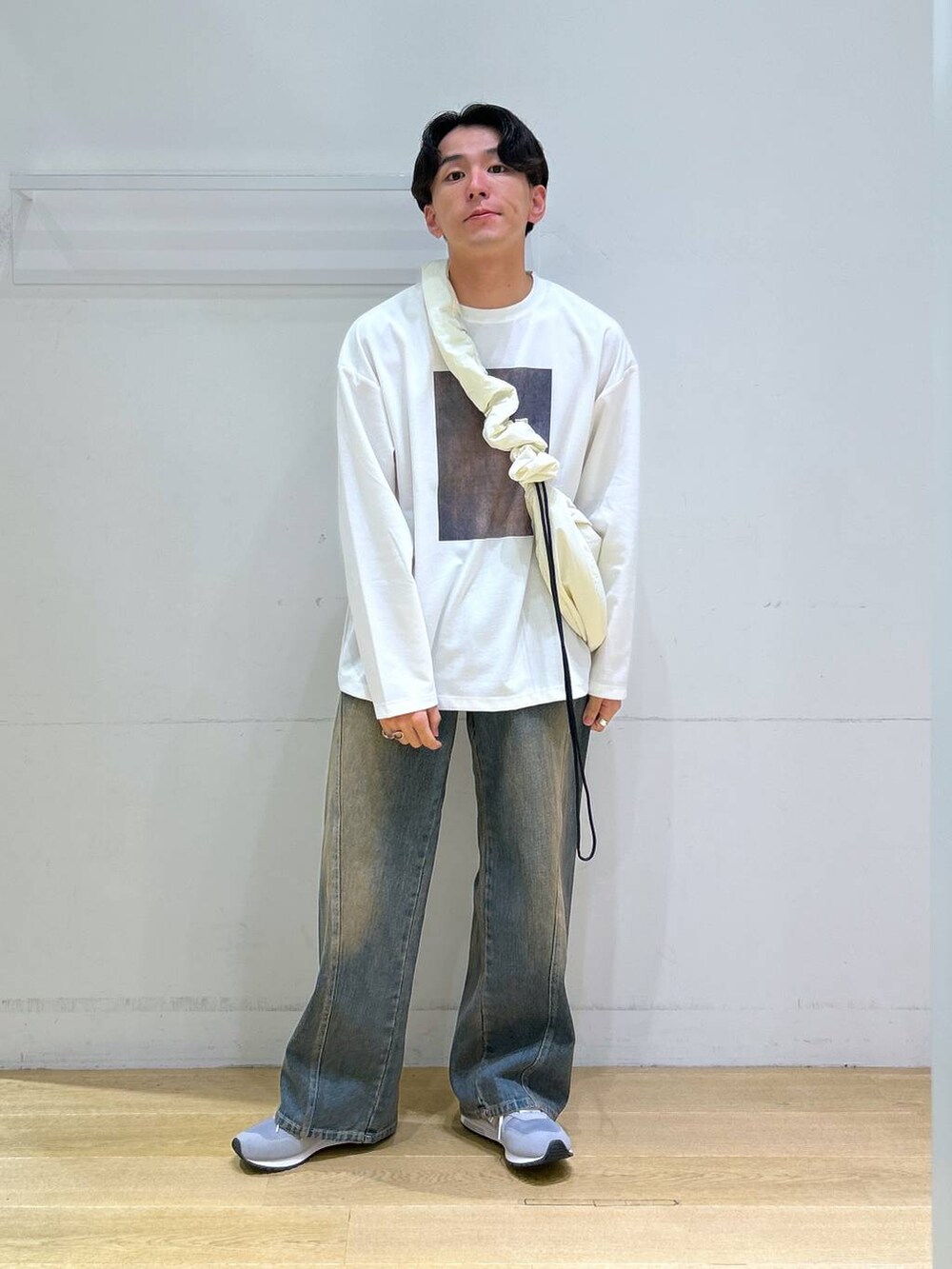 ブルー系のデニムパンツ、ホワイト系のショルダーバッグ、グレー系のスニーカーを着用したメンズの秋コーディネートの5枚目の写真