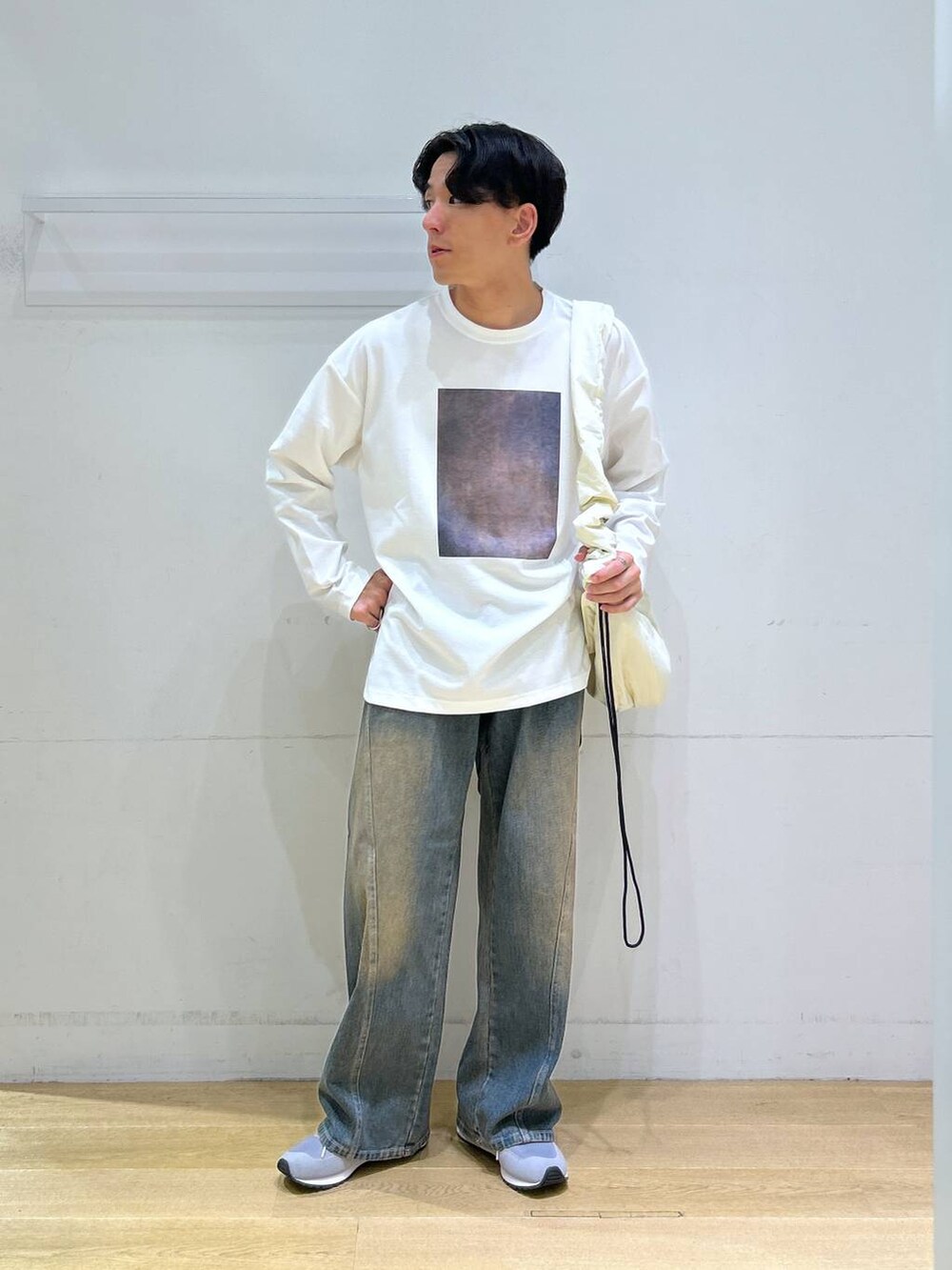 ブルー系のデニムパンツ、ホワイト系のショルダーバッグ、グレー系のスニーカーを着用したメンズの秋コーディネートの3枚目の写真