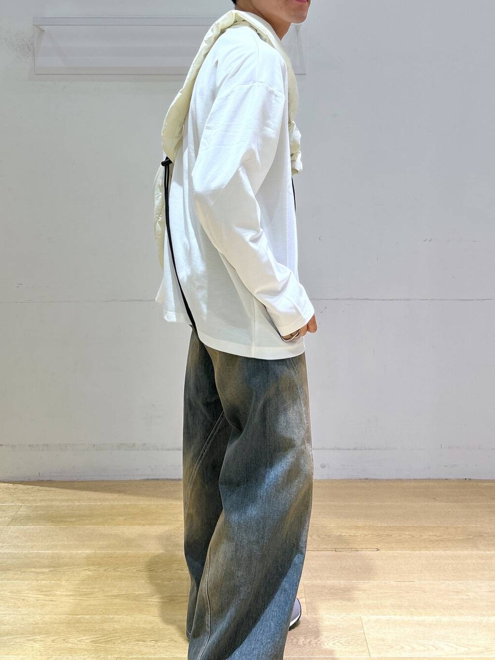 ブルー系のデニムパンツ、ホワイト系のショルダーバッグ、グレー系のスニーカーを着用したメンズの秋コーディネートの2枚目の写真