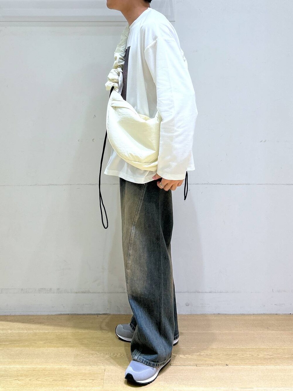 ブルー系のデニムパンツ、ホワイト系のショルダーバッグ、グレー系のスニーカーを着用したメンズの秋コーディネートの4枚目の写真