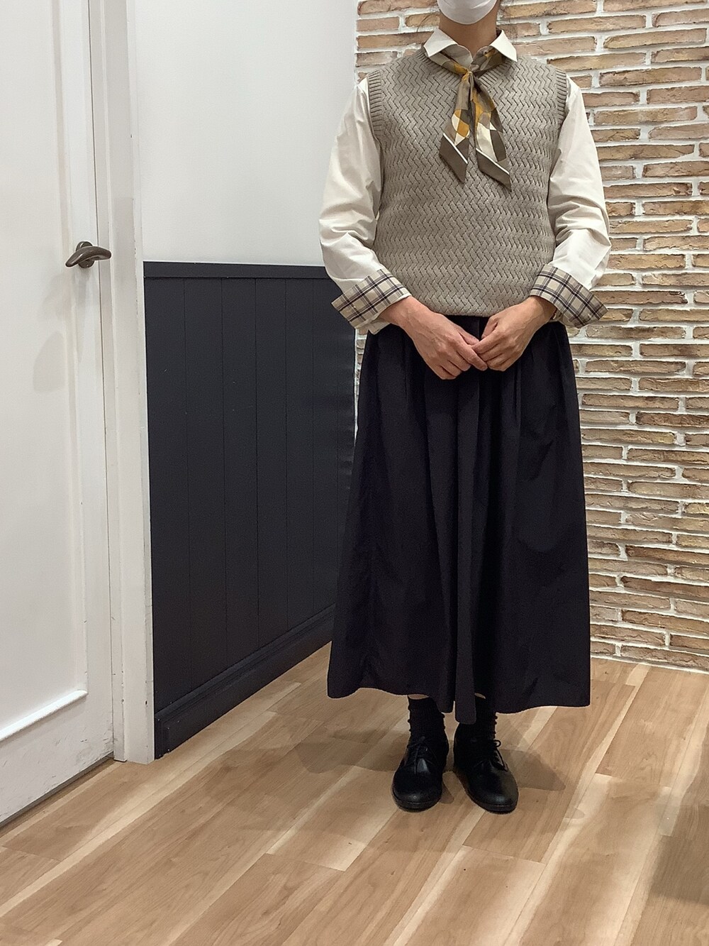 ベージュ系のビジネスシャツ、ベージュ系のニット/セーター、ホワイト系のストール/ショールを着用したレディースの冬コーディネートの2枚目の写真